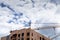 Large construction cranes over a plywood clad building structure, blue sky with gathering storm clouds, creative copy space