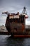 A large container ship is docked at Seaspan, named `Seaspan Survivor`. Cranes are atop this old, rusty ship and large anchor chai