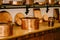 Large copper pots with hot coasters on the countertop with copper saucepans and saucepans on shelves to be attached to