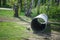 A large corrugated pipe, prepared for installation, lies on the ground in a park or square. Production of storm collector sewers.