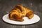 Large croissant placed on a plate on a dark background.