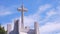 Large Cross Statue on Rooftop of white Church against clouds on blue sky background in widescreen view