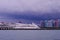 Large cruise ship of Star Cruises docked at Marina Cruise Centre against backdrop of dramatic dark rain clouds