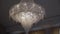 Large crystal chandelier from ceiling with electric lamps. Luxurious interior.