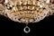 Large crystal chandelier detail isolated on black background.