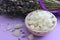 Large crystals of sea salt and lavender flowers, close-up on a purple background.