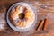 A large cupcake with cinnamon sticks on a wooden surface.