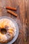 A large cupcake with cinnamon sticks on a wooden surface.