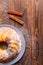 A large cupcake with cinnamon sticks on a wooden surface.