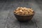 A large deep bowl with unpeeled almonds on a black wooden background