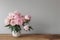 Large delicate pink bouquet of peony flowers with leaves on wooden table.