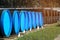 Large-diameter pipes with plugs lie in an open warehouse on a summer day. Storage and supply of gasification materials