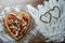 Large diet pizza in the shape of a heart on a wooden table with flour.