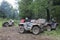 Large dirt-covered ATVs with red cans standing in a coniferous forest