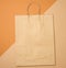 Large disposable brown kraft paper bag with handles on a brown background