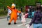 A large doll in the form of an orange bird, the symbol of the Dodo pizzeria-pizza, is photographed with children at the festival