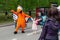 A large doll in the form of an orange bird, the symbol of the Dodo pizzeria-pizza, is photographed with children at the festival