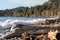 Large driftwood log and rocks on the coast with large waves breaking on the coast of the Pacific Ocean on Vancouver Island