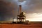 A large drilling rig for oil or gas production in a hot desert terrain against of a thundercloud. Generative AI