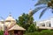 Large Egyptian orthodox white church with crosses, arches, domes and prayer windows against the backdrop of green trees and palm t