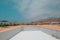 Large empty hotel swimming pool without water in Legzira, Morocco. Blue day sky, huts, mountain views all around. Closed for the