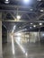 Large empty warehouse inside in industrial building with a high ceiling and artificial lighting