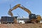 A large excavator dumps dirt into a truck