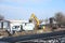 Large excavator filling a dump truck with rock and soil for road repairs.