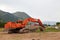 Large excavator with a lowered bucket during repair work in the mountains on a summer day