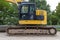 A large excavator in yellow color visible from the profile with a lowered bucket.