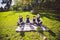 Large family Caucasian children. Three brothers and sister sitting resting on blanket outside the park. Green lawn grass