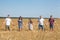 Large family from father, mother, two brothers and sister holding hands in line on a wheat field, full length portrait