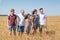 Large family from father, mother, two brothers and sister standing in line on wheat field, full length portrait