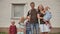 A large family with four children in front of their own home.