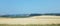 Large field of brown hay or grass and a stack of hay bales