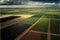 a large field of crops under a cloudy sky with a plane flying over it and a few clouds in the sky