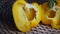 Large fresh yellow pepper, cut in half on a cane round tablecloth