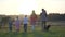 A large friendly family walks across the field at sunset with dogs.