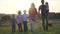 A large friendly family walks across the field at sunset with dogs.