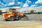 A large front loader transports crushed stone or gravel in a bucket at a construction site or concrete plant. Transportation of