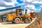 A large front loader transports crushed stone or gravel in a bucket at a construction site or concrete plant. Transportation of