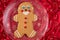 Large gingerbread cookie on a glass platter, red fabric background with gold snowflakes