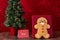 Large gingerbread cookie on a red background, Christmas tree with white lights, note to Santa, on a wood table