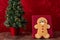 Large gingerbread cookie on a red background, Christmas tree with white lights, on a wood table