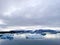 a large glacier melting in the ocean with a sky filled with clouds