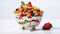 A large glass bowl filled with a variety of fresh fruits including strawberries, blueberries, blackberries, peaches, and kiwi