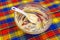 Large glass bowl with leftovers of batter and plastic spatula on colorful towel background