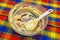 Large glass bowl with leftovers of batter and plastic spatula on colorful towel background