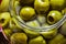 Large glass jar of green pitted olives closeup detail