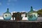 Large glass jars outside on ledge reflecting whitewashed buildings and blue sky